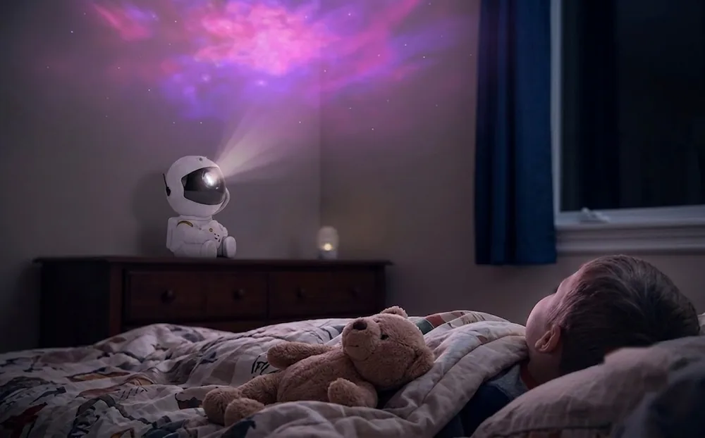 Niño acostado en su cama mirando la luz suave del proyector en el techo
