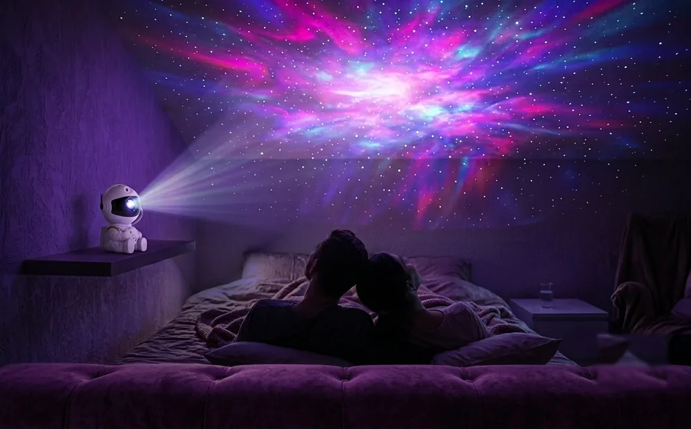 Pareja recostada en la cama mirando la nebulosa proyectada en el techo